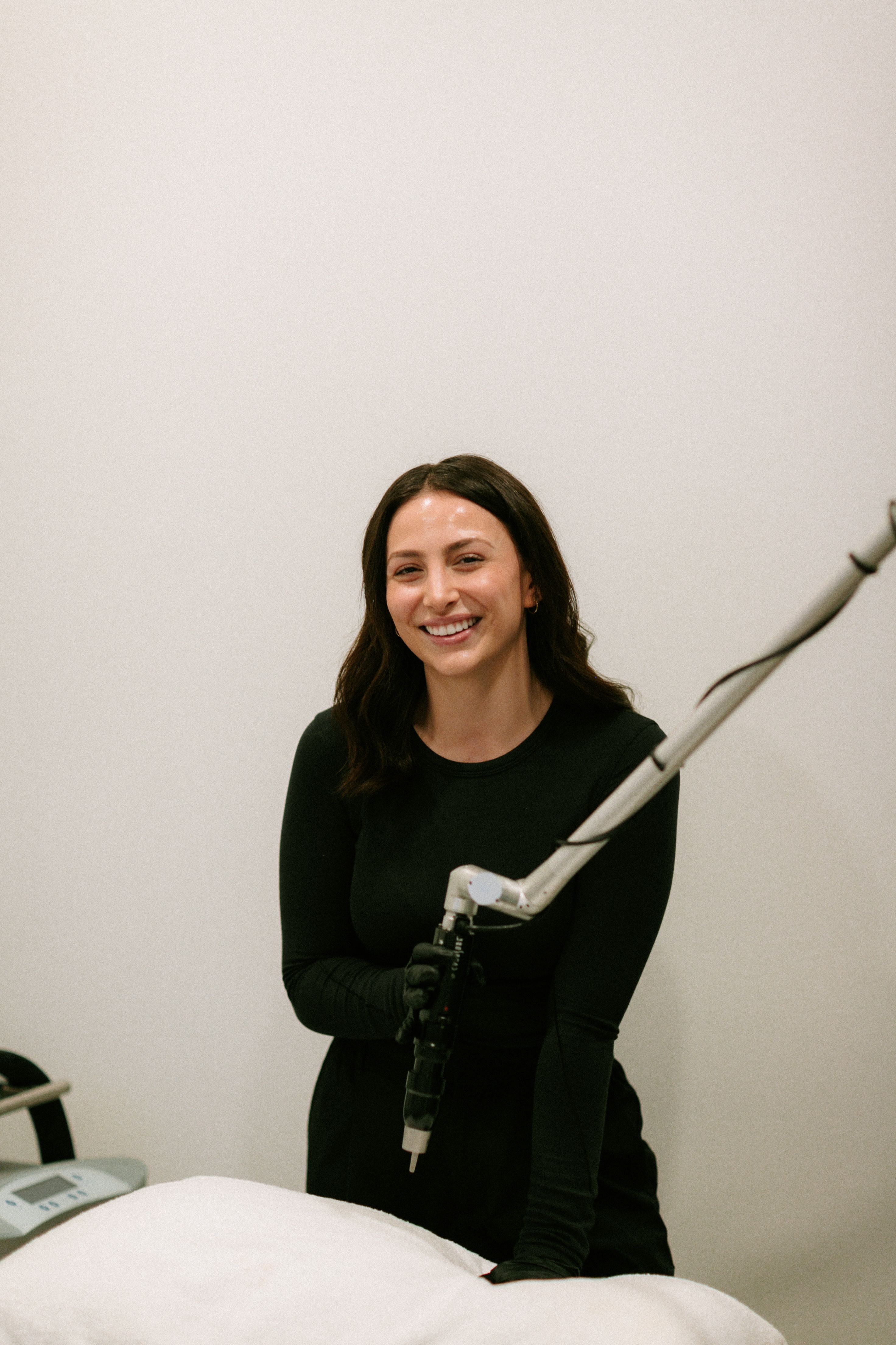 LA Medspa clinician holding laser equipment, softly lit against a cream wall