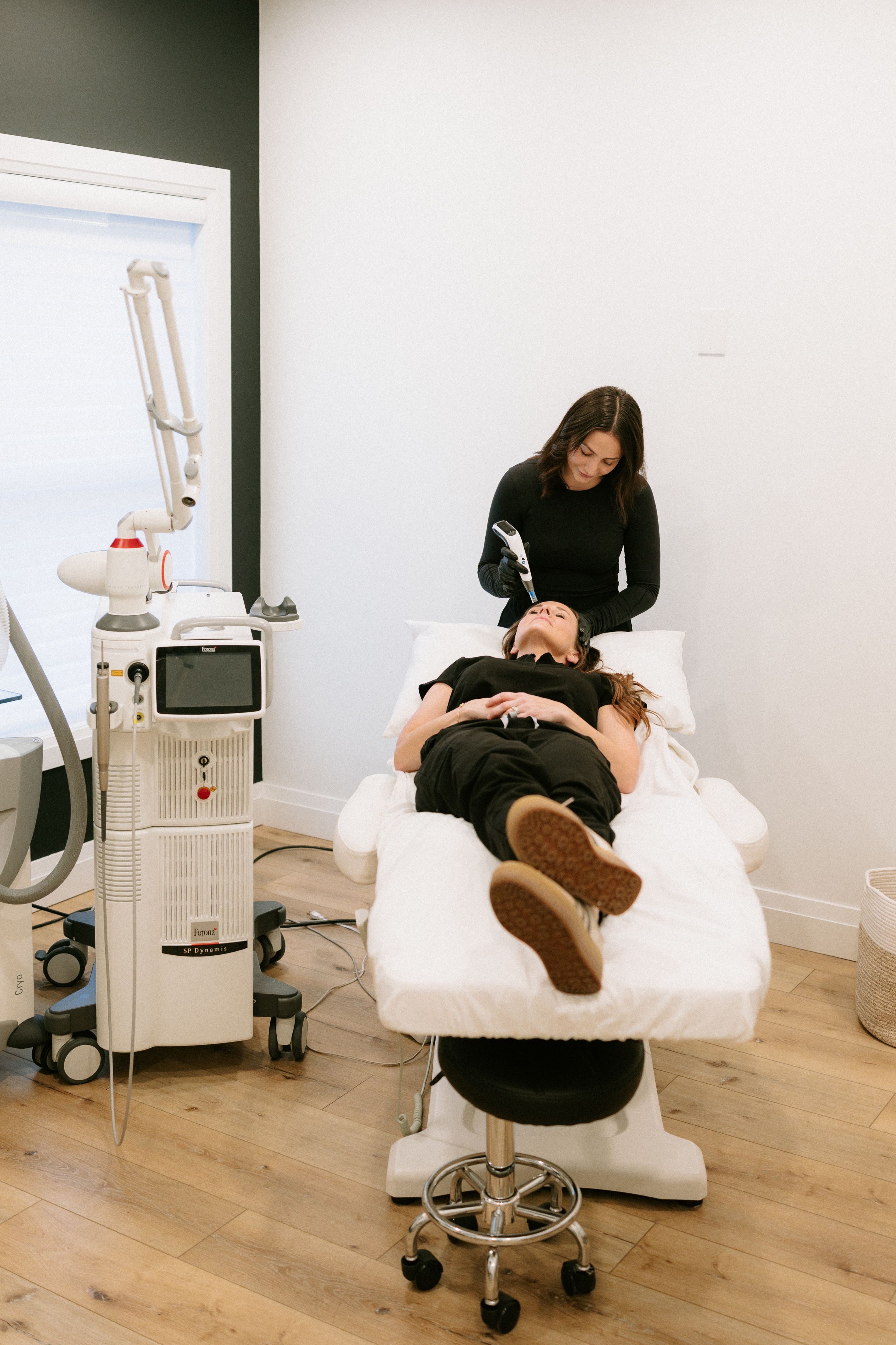 Two clinicians at a glass consultation table with natural light and an olive tree